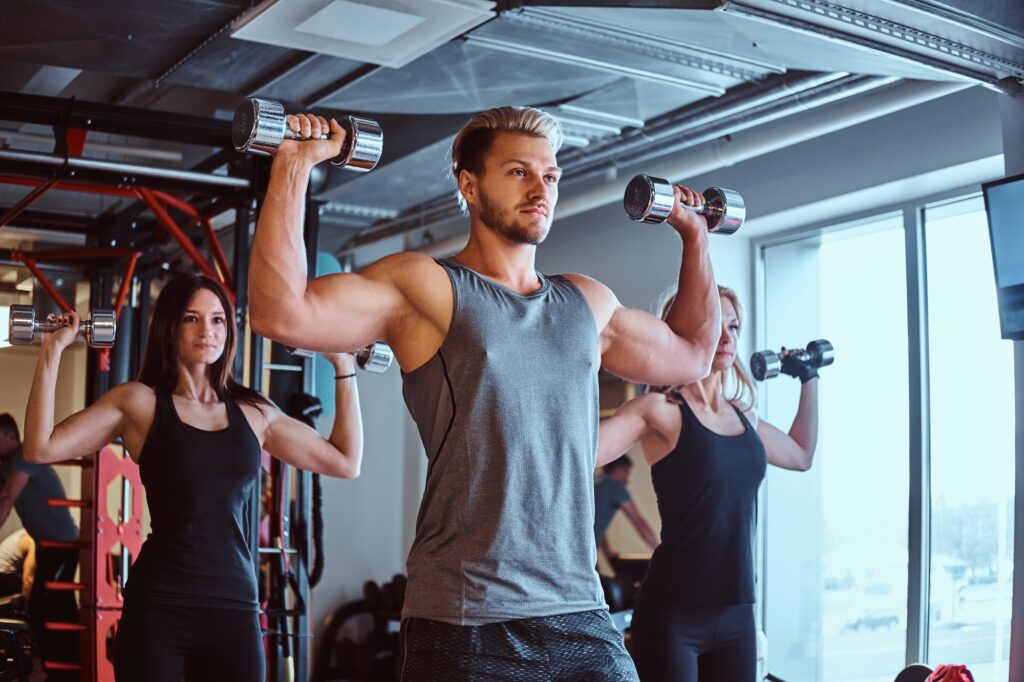Group of people exercising with dumbbells in a fitness club or gym.