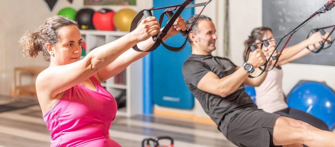 People doing exercises with trx fitness straps at gym. Concept of trx exercises.